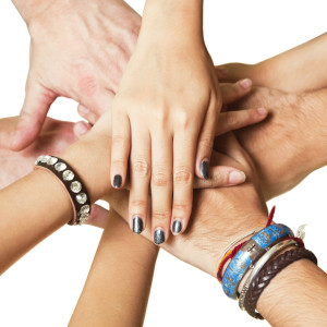 Close-up of human hands clasped together in unity against white backdrop